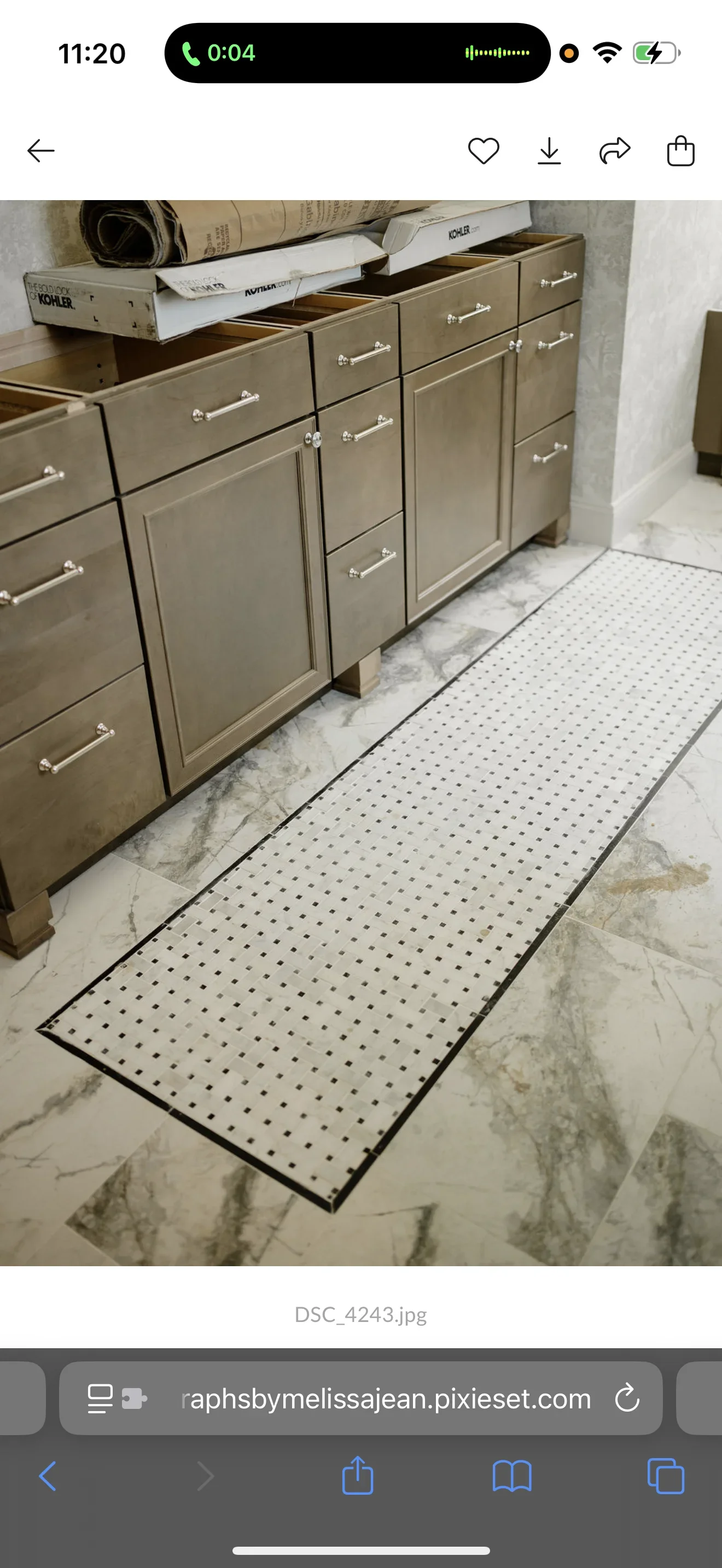 Marble bathroom floor with black border and dot-pattern inlay runner beneath taupe cabinetry