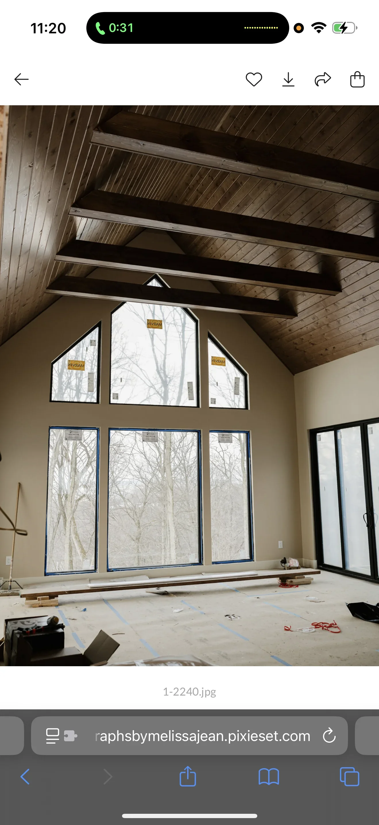 Vaulted ceiling with exposed beams, neutral painted walls, and large multi-pane windows with blue frames