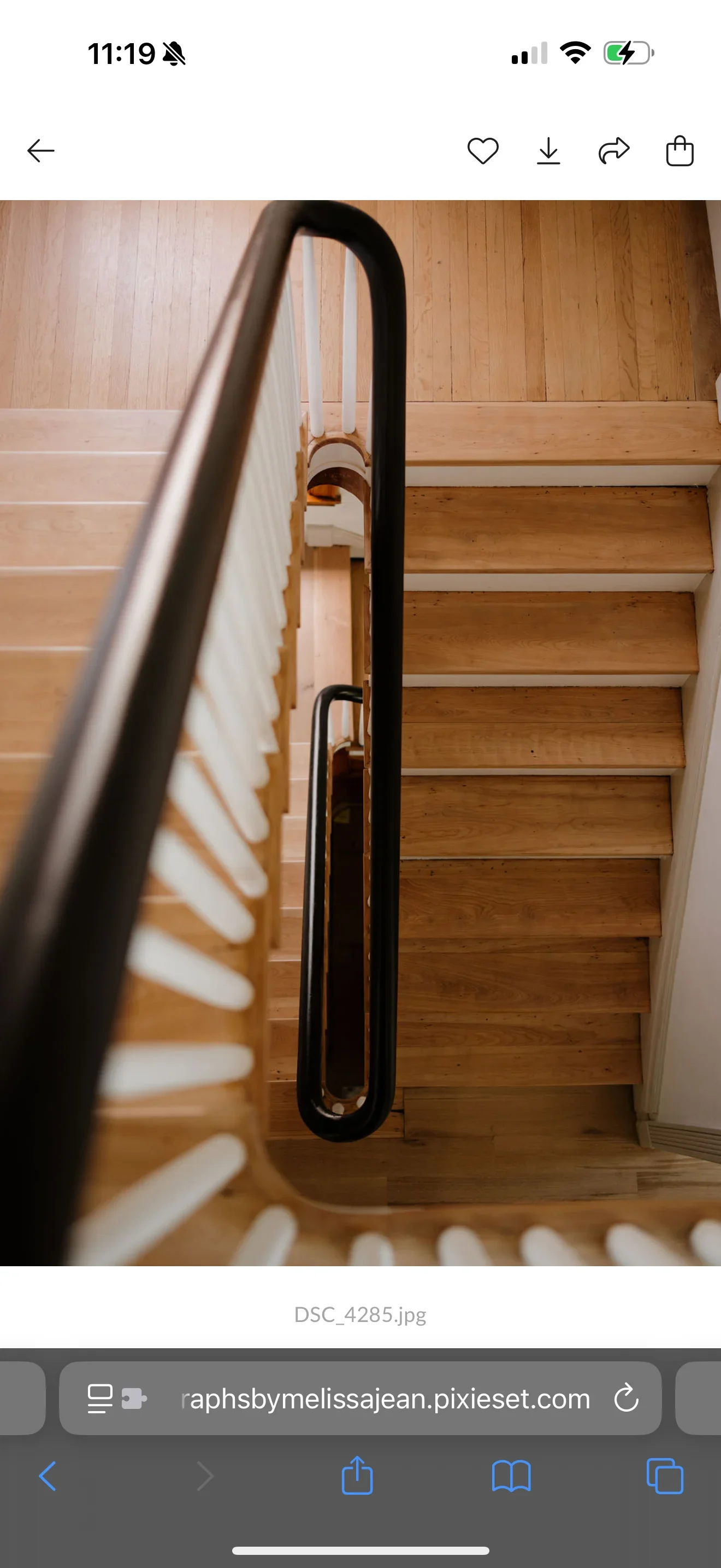 Wooden staircase with white paneling and black metal curved railing