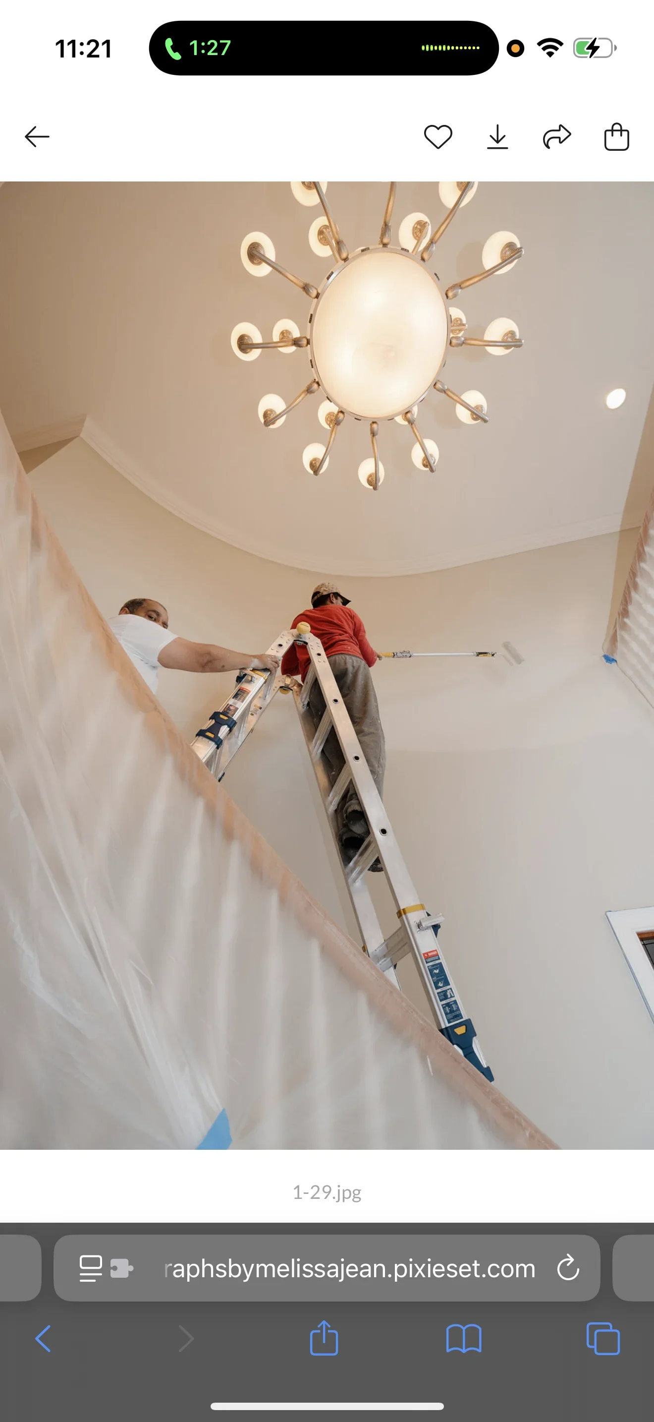 Worker on ladder finishing curved drywall ceiling with brass starburst pendant light fixture