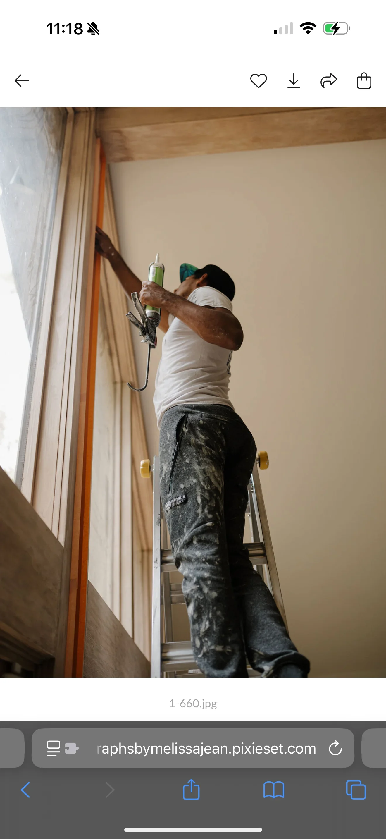 Painter on ladder spraying cream paint on interior drywall wall